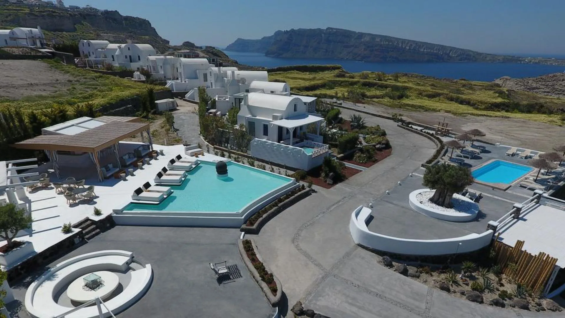 Aerial view of Oia Sunset Villas, its pools and the Aegean beyond
